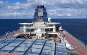 <i>Celebrity Infinity</i>.<br>Vue de la <i>Breeze Pool</i>. Au premier plan, le toit vitré de l'Aquaspa. Juste devant la cheminée, le Conservatory. La bande rouge peinte sur le sol matérialise la piste de jogging (1/3 km par tour).