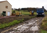 Le camion bétonnière à toupie ne craint pas la boue car toutes ses roues sont motrices. On ne peut pas en dire autant du camion benne chargé de tracter la pompe à béton: il faudra l'aide du tracteur du paysan du coin pour le sortir de la mélasse !