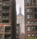New York<br>L'Empire State Building émergeant de la brume, entre deux immeubles un peu délabrés.